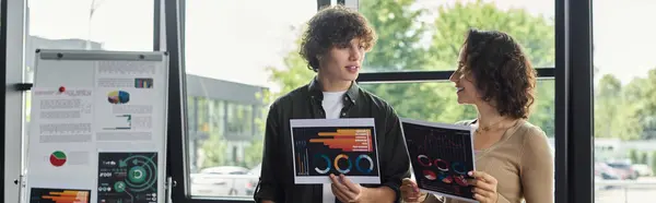 Two professionals present colorful reports while engaging in a discussion in an office environment. — Stock Photo