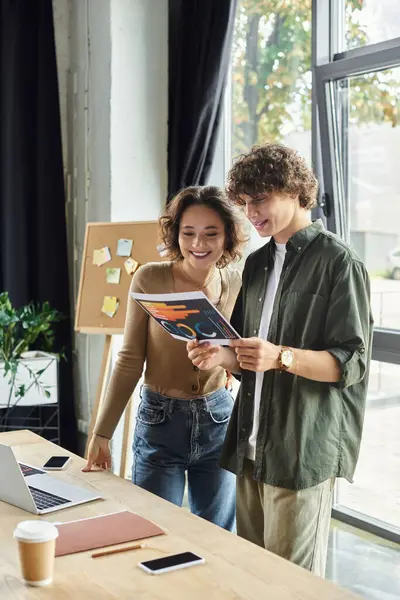 Zwei Kollegen arbeiten an einem Dokument an einem hellen Schreibtisch im Büro und zeigen Teamwork. — Stockfoto