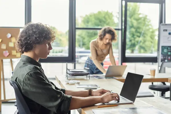 Zwei Kollegen arbeiten in einem hellen Büroraum zusammen, während sie ihren Aufgaben nachgehen. — Stockfoto
