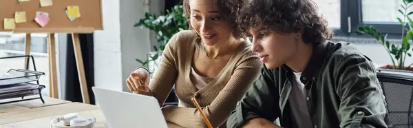 Two coworkers exchange ideas while working on a laptop in a modern office. — Stock Photo