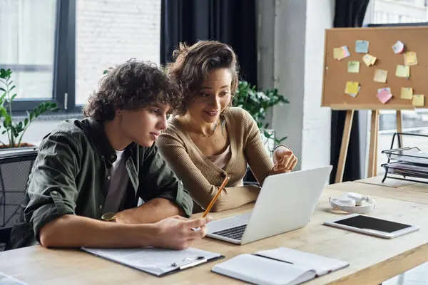 Two colleagues engage enthusiastically over a laptop while brainstorming ideas in a modern office. — Stock Photo
