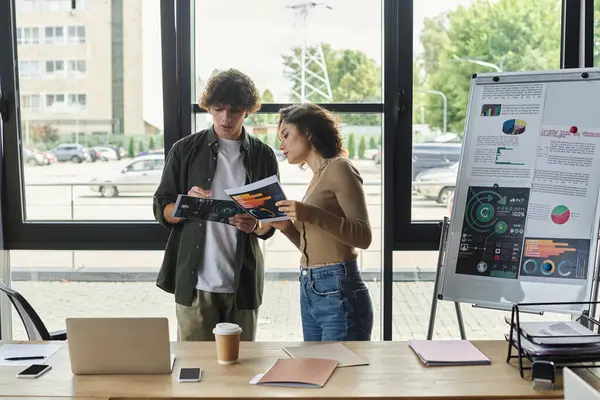 Two colleagues discuss and brainstorm ideas while reviewing documents together. — Stock Photo