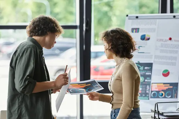 Deux collègues analysent les graphiques et les données dans un bureau moderne, engageant une discussion productive. — Photo de stock