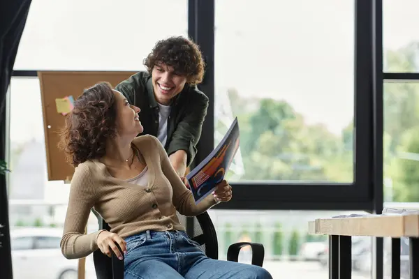 Two coworkers share a joyful interaction while collaborating on a creative project in an office. — Stock Photo