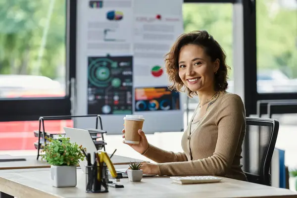 Dedicated professional smiles while sitting at a well organized office desk with a coffee cup. — Stock Photo