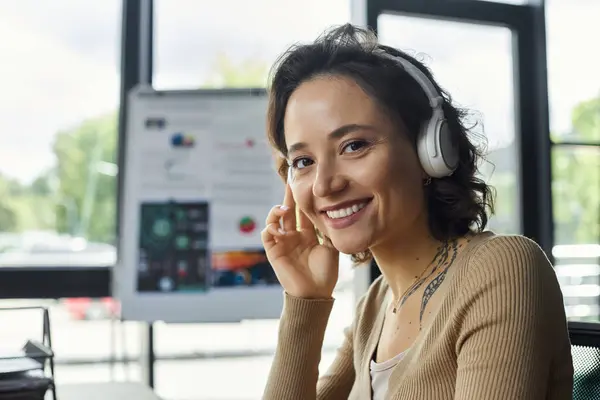 A woman immersed in her work wears headphones in a bright, modern office. — Stock Photo