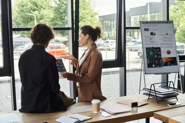 Two professionals analyze project data on a tablet in a modern office. — Stock Photo