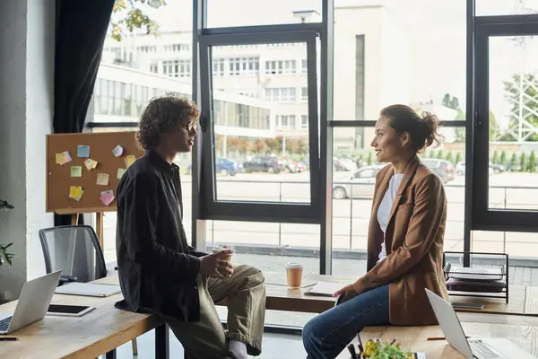 Two coworkers share ideas over coffee in a spacious office filled with natural light. — Stock Photo