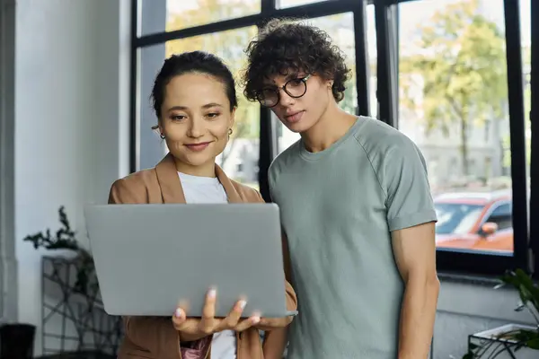 Zwei Personen arbeiten in einem modernen Arbeitsbereich um einen Laptop herum und unterstreichen die Teamarbeit. — Stockfoto