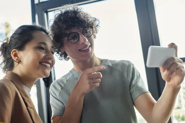 Zwei Mitarbeiter teilen einen hellen Moment, während sie Ideen in einem hellen Büroumfeld diskutieren. — Stockfoto