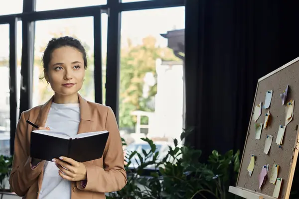 A professional woman takes notes while observing her organized workspace filled with inspiration. — Stock Photo