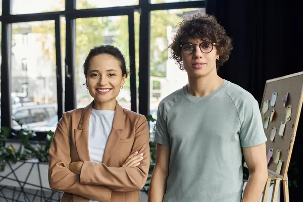Two professionals stand confidently in a bright office, surrounded by greenery and creativity. — Stock Photo