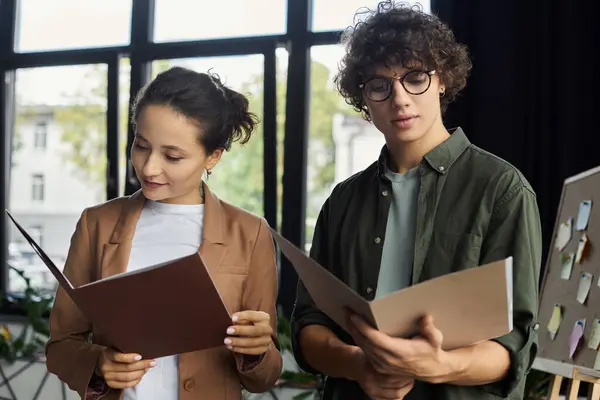 Two colleagues engage in an inspiring discussion while reviewing documents in a bright office. — Stock Photo