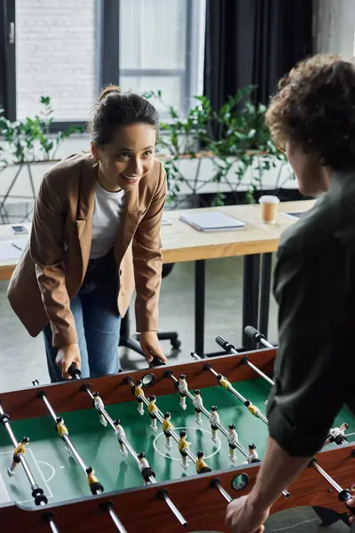 Colleagues enjoy a friendly foosball game, sharing laughter in a welcoming office. — Stock Photo