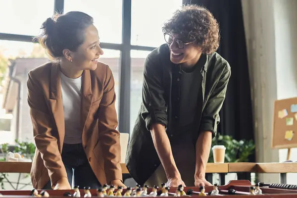 Colleagues share laughter and strategy while enjoying a foosball game in a modern workspace. — Stock Photo