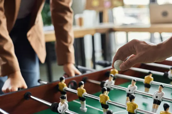 Two colleagues focus intently on a foosball game, showcasing teamwork and lighthearted competition. — Stock Photo