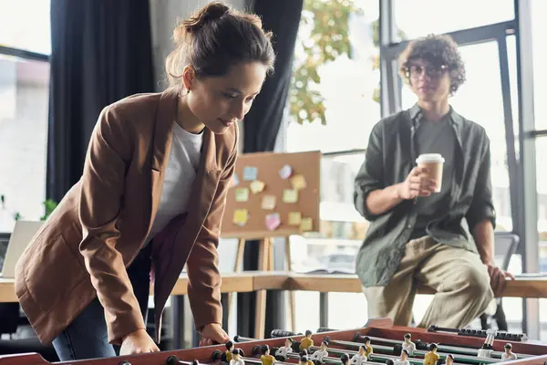Colegas toman un momento para relajarse y disfrutar de un juego de futbolín animado en un espacio de trabajo moderno. - foto de stock