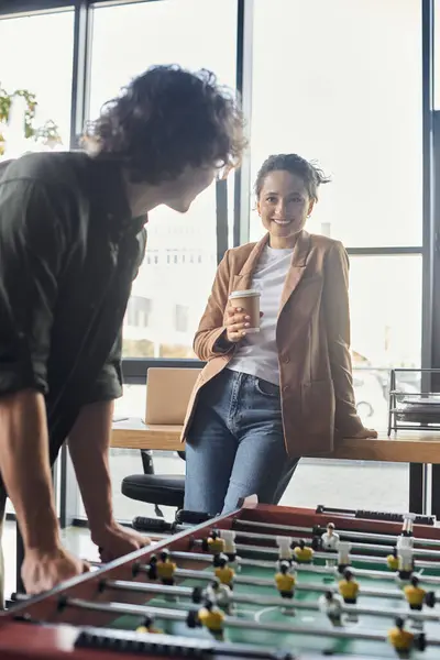 Kollegen genießen ein verspieltes Kickerspiel, während sie in stilvollem Büroambiente Kaffee schlürfen. — Stockfoto