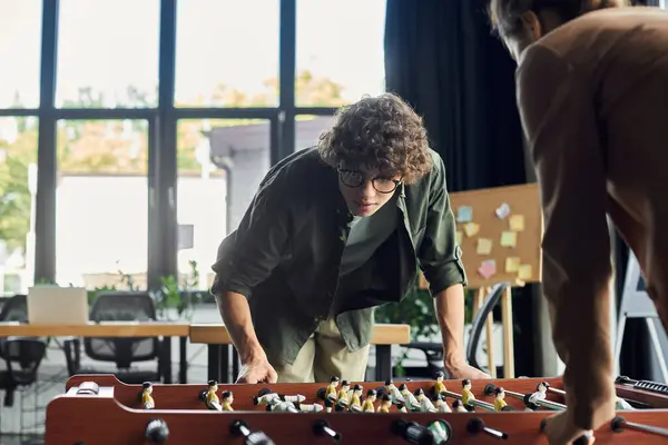 I colleghi godono di una amichevole competizione di calcio balilla, favorendo il lavoro di squadra e il relax in ufficio.. — Foto stock
