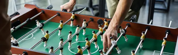 Hands skillfully navigate the foosball table as coworkers engage in a lively match at the office. — Stock Photo
