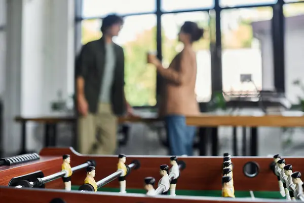 Colleagues share ideas and laughter in a spacious office, a foosball table in the foreground. — Stock Photo