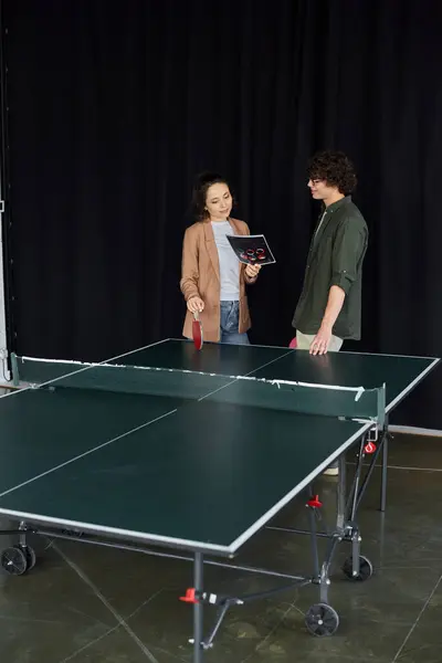 Two professionals in a casual office setting discuss strategies next to a table tennis setup. — Stock Photo