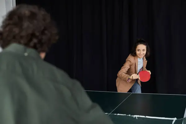 Two coworkers play an energetic game of table tennis, showing teamwork and fun at work. — Stock Photo