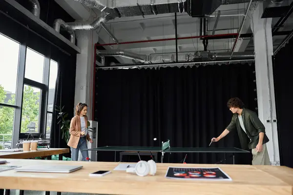 Two colleagues play table tennis in a modern office, boosting teamwork and fun. — Stock Photo