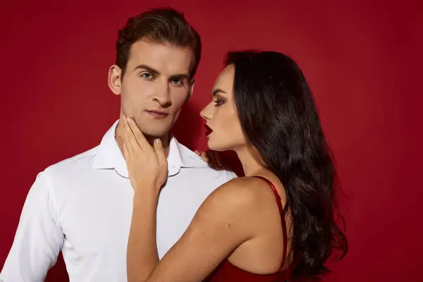 A couple shares an alluring moment, radiating love and passion, against a vibrant red backdrop. — Stock Photo