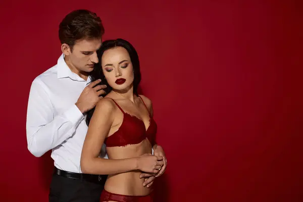 Um casal está de perto, irradiando amor e paixão, cercado por um impressionante fundo vermelho. — Fotografia de Stock