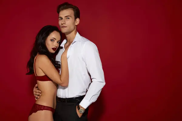 A couple enjoys their passion against a vibrant red backdrop, highlighting their chemistry. — Stock Photo