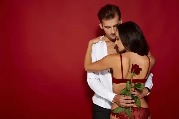 A couple shares a loving moment against a striking red background. — Stock Photo