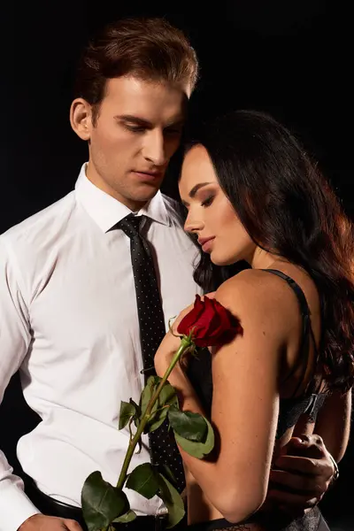 A couple stands closely, eyes locked, sharing an intimate moment while holding a rose. — Stock Photo