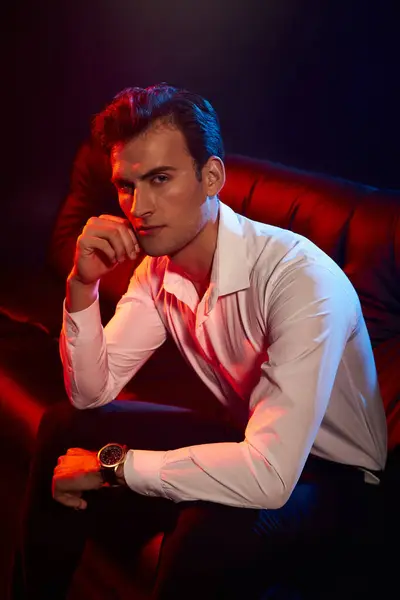 Admire a stylish young man relaxed on a luxury couch, exuding charm and elegance. — Stock Photo