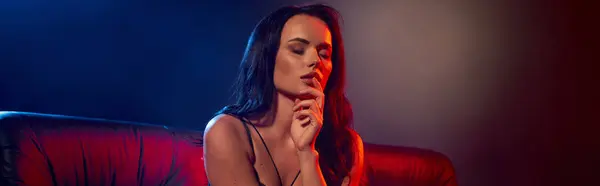 Uma jovem mulher deslumbrante exala charme e fascínio enquanto se senta suavemente em um espaço acolhedor e mal iluminado. — Fotografia de Stock