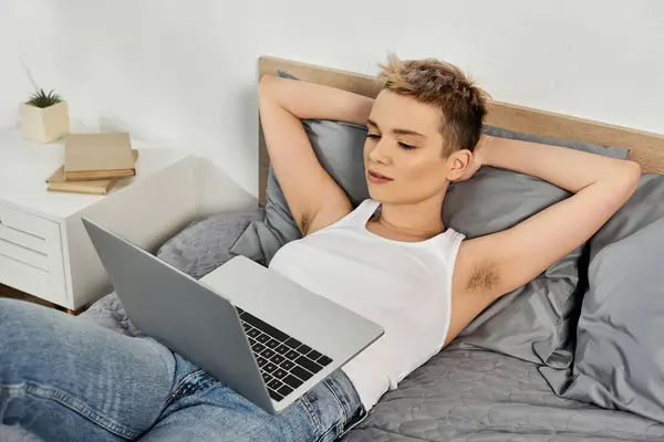 A beautiful young woman relaxes in bed with a laptop, exuding body positivity and confidence. — Stock Photo