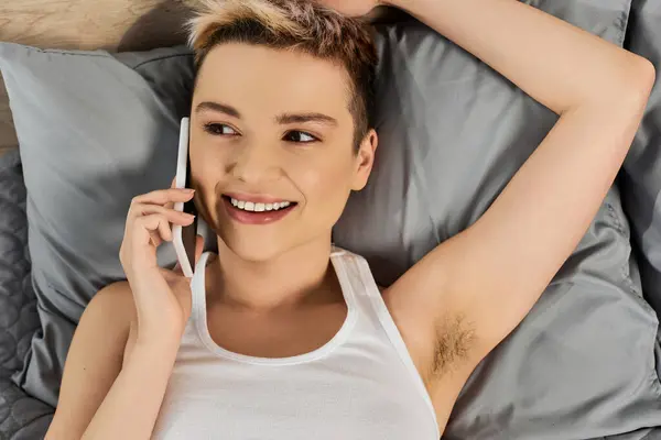 Bright smile illuminates her face as she comfortably holds a phone, enjoying a casual chat. — Stock Photo