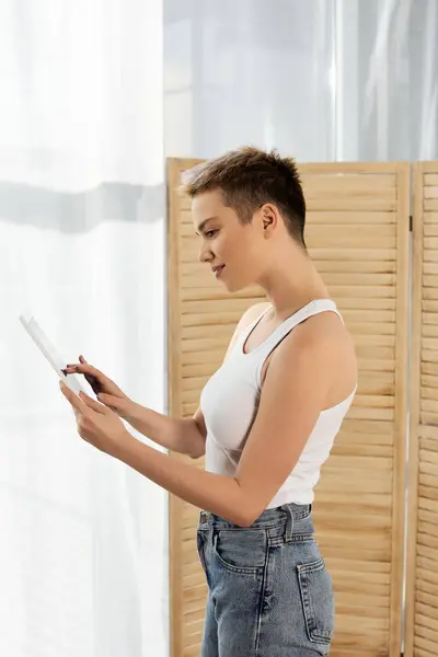 Confident woman enjoying a quiet moment while reading against a wooden backdrop in bright light. — Stock Photo