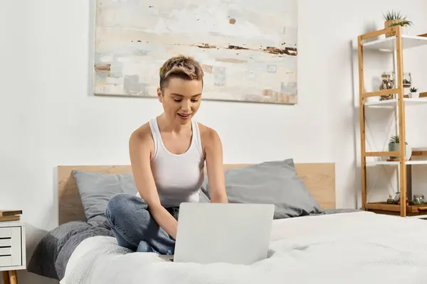 A young woman radiates positivity while working on her laptop in a stylish bedroom. — Stock Photo
