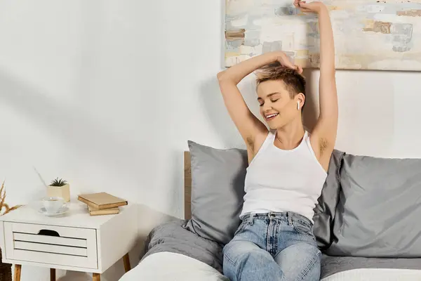 A young woman smiles brightly while stretching in her stylish bedroom, embracing body positivity. — Stock Photo