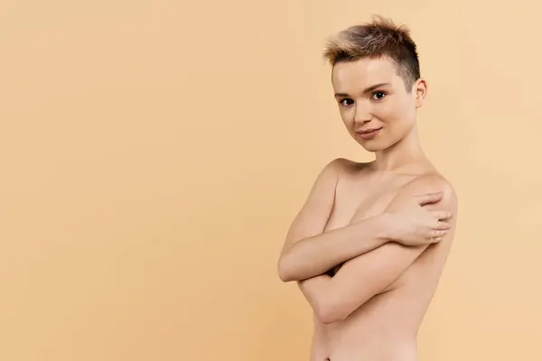 Eine junge Frau steht anmutig und präsentiert ihren selbstbewussten Körper in einer warmen Umgebung. — Stockfoto