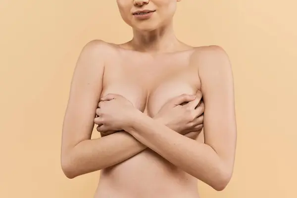 Una joven confiada abraza su belleza, irradiando positividad corporal contra un telón de fondo suave. - foto de stock