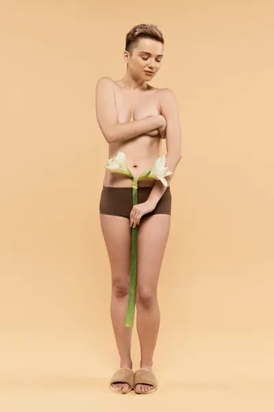 Une jeune femme embrasse son corps, rayonnant de confiance avec des fleurs délicates ornant sa taille. — Photo de stock