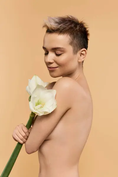 A young woman expresses body positivity while gently holding a flower in a soft setting. — Stock Photo