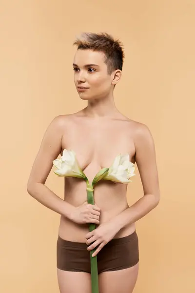 Une belle jeune femme se tient fièrement, célébrant la positivité du corps tout en tenant des fleurs. — Photo de stock