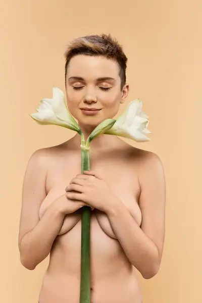 A confident woman holds flowers, radiating self love in a tranquil scene. — Stock Photo