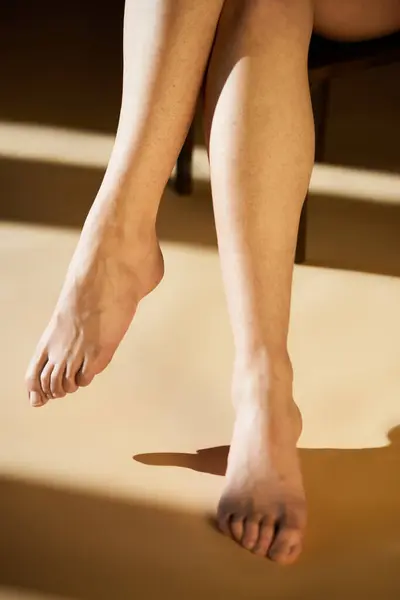 Una giovane donna trasuda positività del corpo mentre si rilassa gioiosamente con i piedi nudi in luce calda. — Foto stock