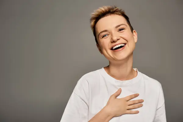 Una joven alegre expresa positividad corporal mientras posa elegantemente en una iluminación suave. - foto de stock