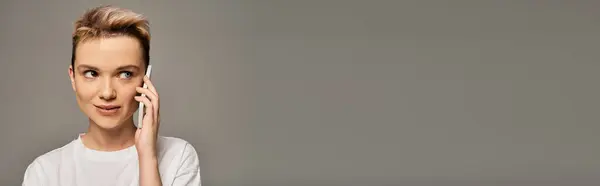 Una hermosa joven charla en su teléfono con una expresión alegre, irradiando confianza. - foto de stock