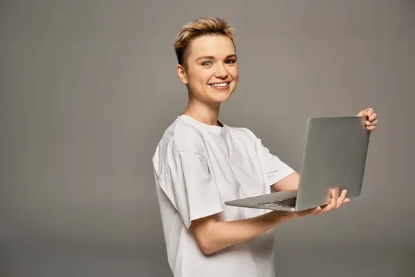 A beautiful woman with a radiant smile stands proudly holding a laptop in a stylish setting. — Stock Photo